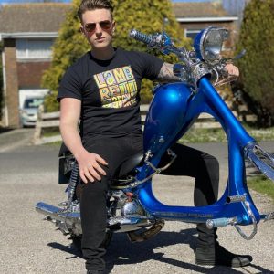 Model sitting on a Lambretta Chopper wearing a Happy Mondays style Lambretta black t-shirt