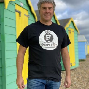 Male model posing on the beach wearing a black Filtrate oil t-shirt